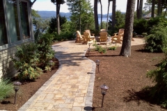 After picture of paver patio and fire pit installed in New Hampshire’s Lakes Region Landscape lighting was installed by the homeowners